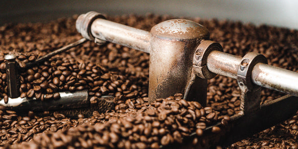 Vintage coffee roasting machine on a bed of roasted coffee beans