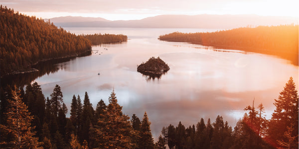 Lake surrounded by trees with a small island in the middle, sunset or sunrise light.
