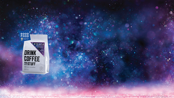 Coffee bag labeled 'Drink Coffee Too' against a cosmic background